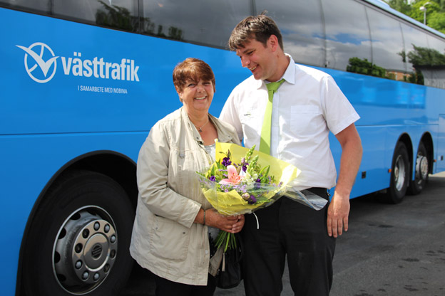 Niclas Höglund, gruppchef på Nobina Skaraborg, delar ut blommor till kunden Ann-Britt Lundqvist från Töreboda, och tackar henne för att hon åkt tagit bussen i 37 år. Foto: Nobina.